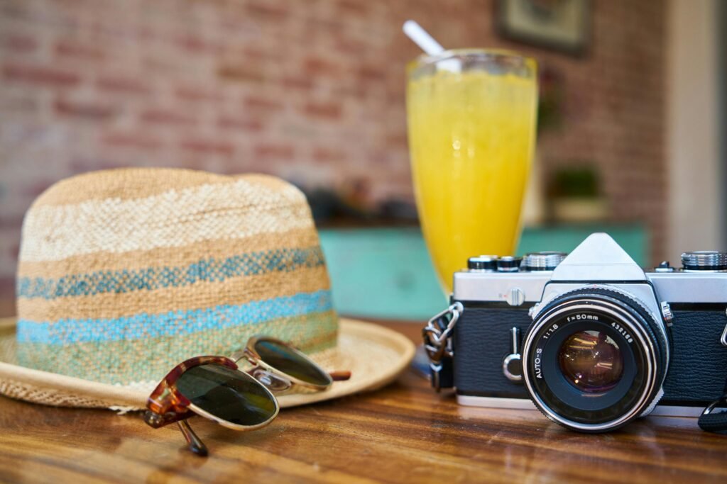 Gray and Black Dslr Camera Beside Sun Hat and Sunglasses ready for an all-inclusive vacations